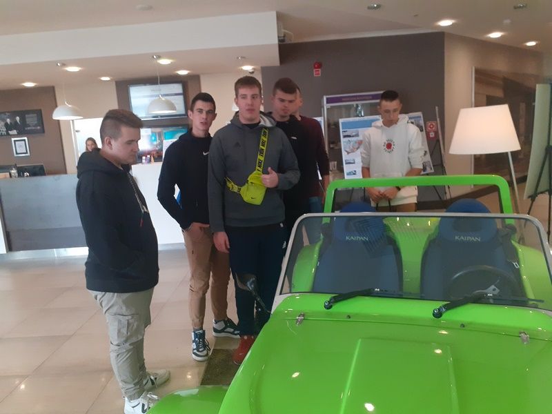 Uczniowie wokół modelu samochodu elektrycznego.